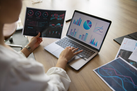 Mulher trabalhando em um computador, com gráficos e planilhas visíveis na tela. A imagem ilustra o estudo e a aplicação da Matriz GE/McKinsey para análise estratégica.