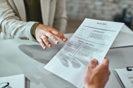 Foco na mão de um colaborador entregando seu currículo durante uma entrevista de emprego.