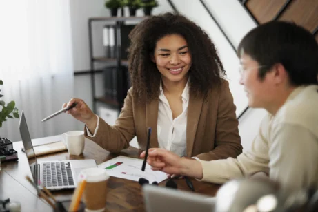 Profissional de RH realizando uma consultoria de carreira. Ambos estão em uma mesa analisando as estratégias da consultoria.