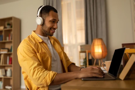 Pessoa estudando online, usando fones de ouvido e laptop, representando a busca por conhecimento em uma formação em RH.