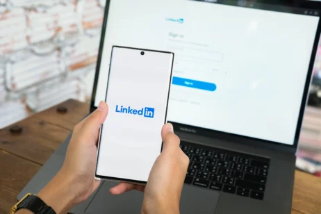 Tela do computador e celular com um perfil do LinkedIn aberto, em referência as estratégias para se destacar na plataforma.