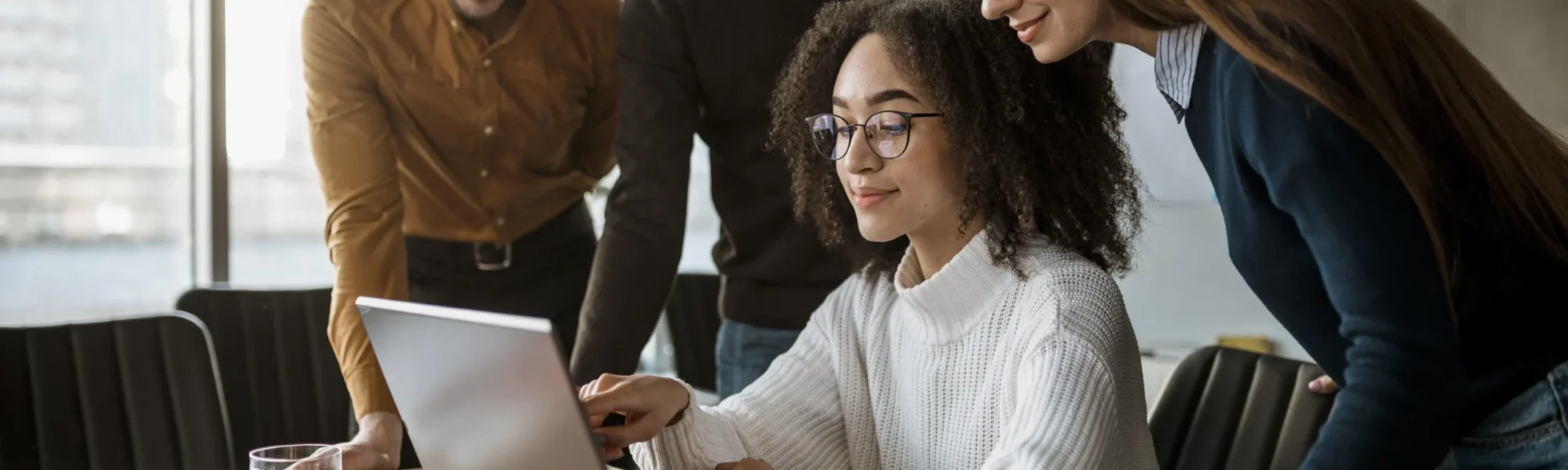 Profissionais de recursos humanos reunidos ao redor de um laptop, discutindo estratégias de gestão digital de pessoas. Transformação digital no RH.